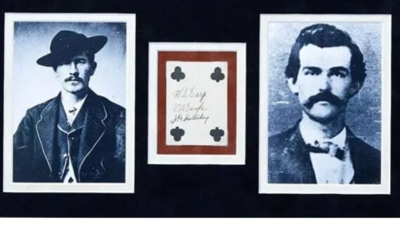 Framed photos of Wyatt Earp and Doc Holliday flanking a playing card with the clubs suit and their handwritten signatures.