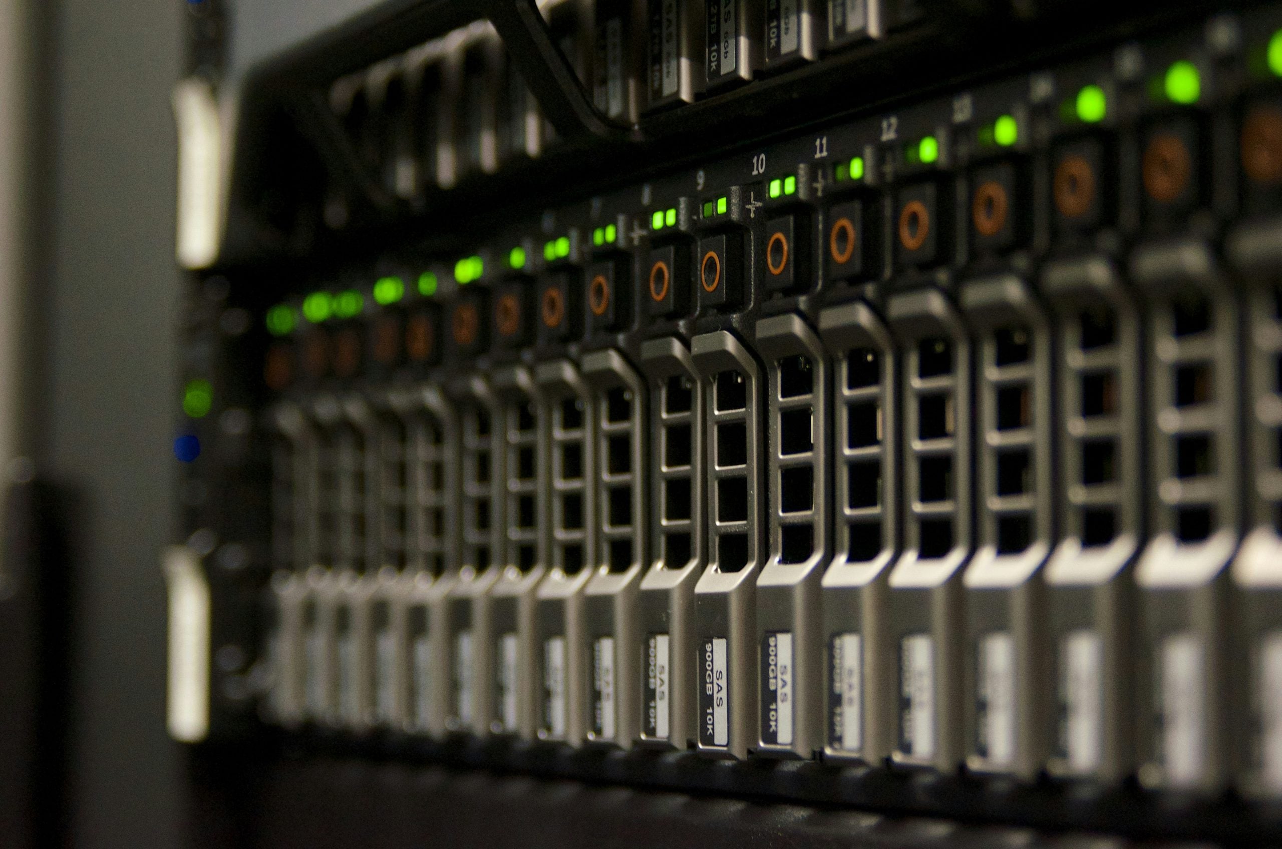A row of server hard drives in a rack, each with a green status light.