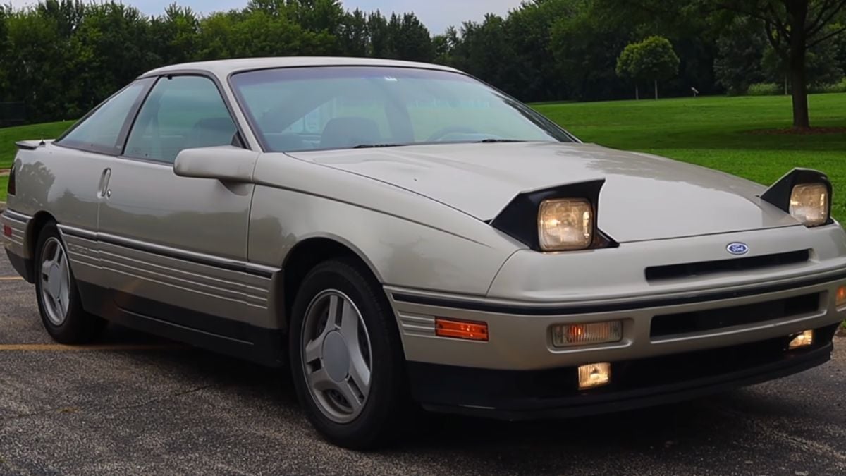A silver Ford Probe coupe with pop-up headlights turned on.