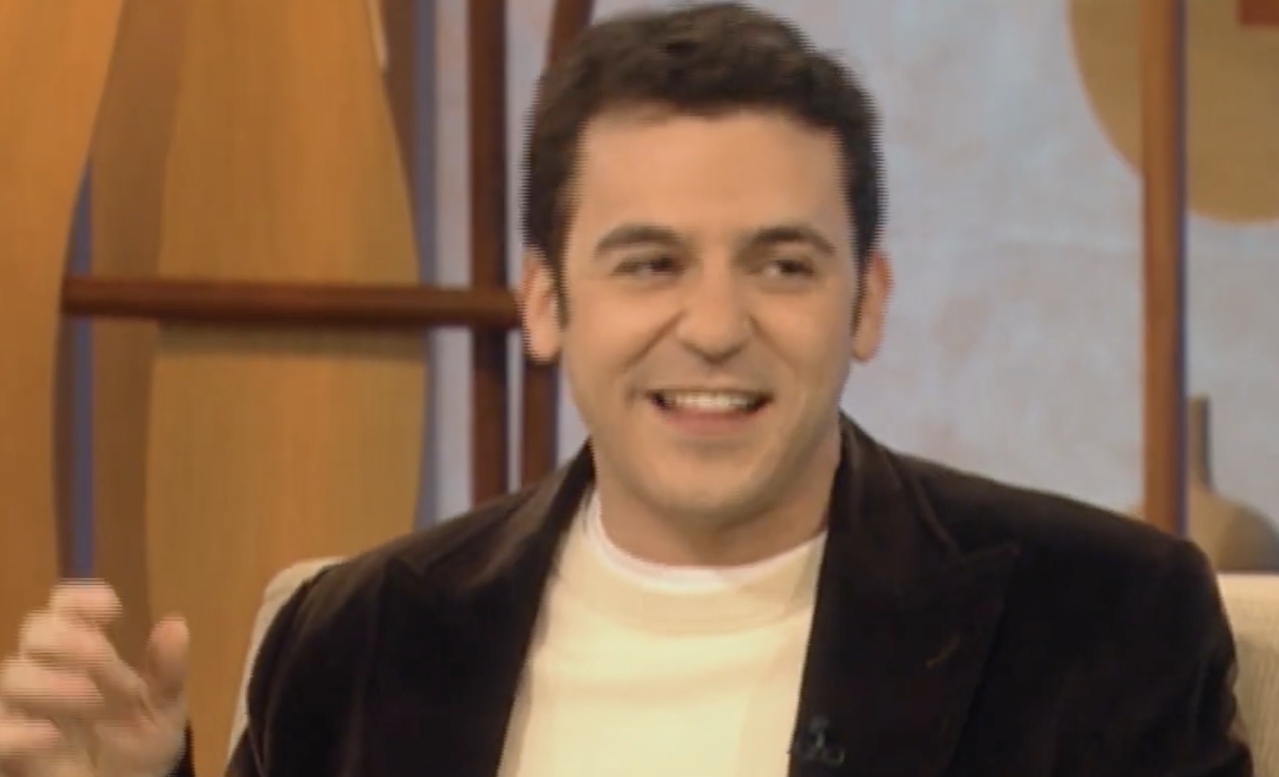 Fred Savage smiling while seated during an interview.