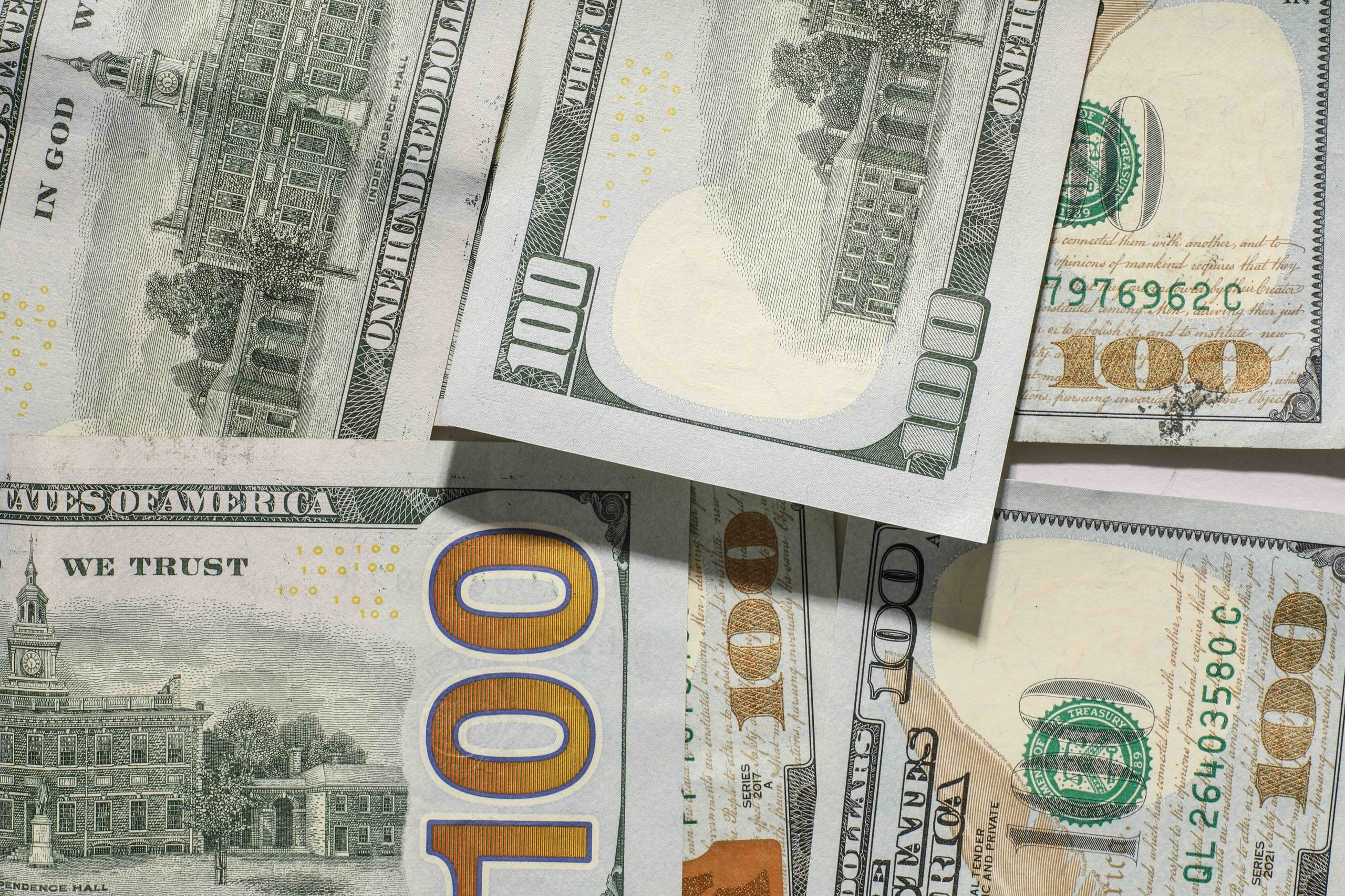 A collection of overlapping U.S. one-hundred-dollar bills.