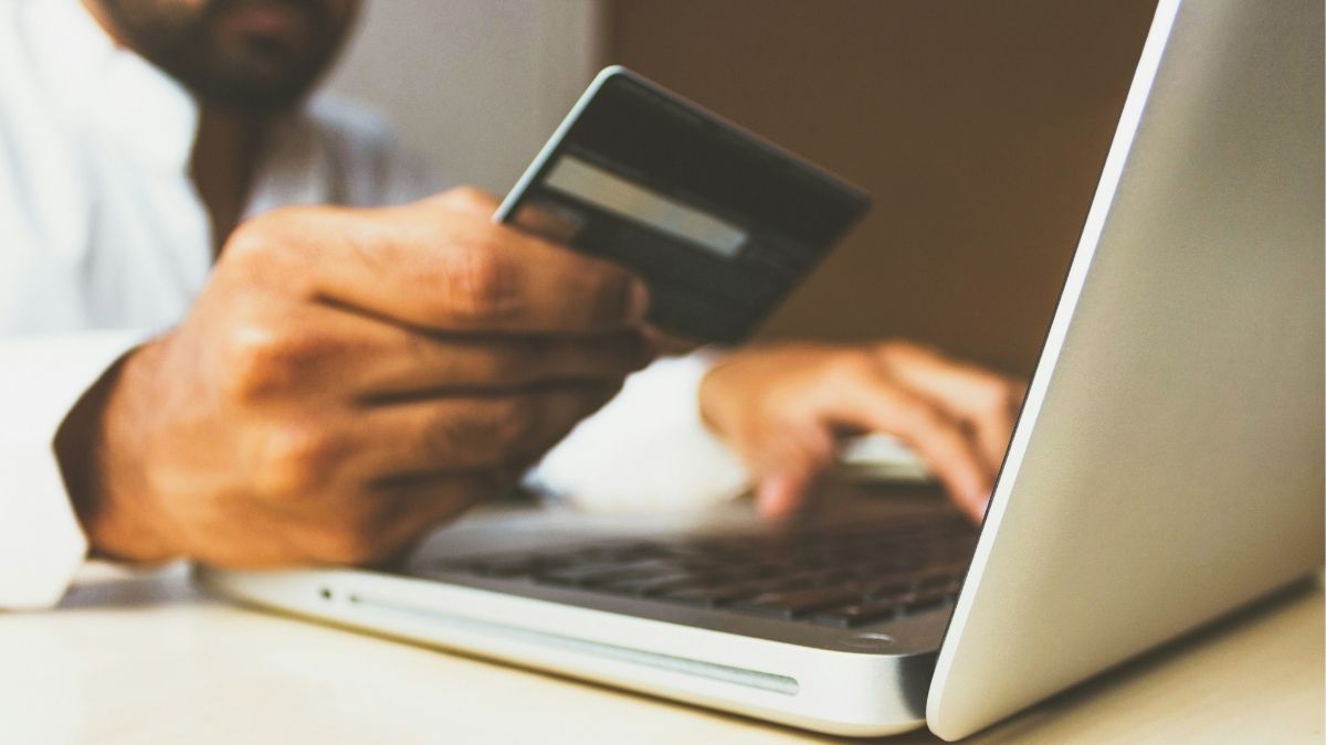 A person holding a credit card while typing on a laptop.