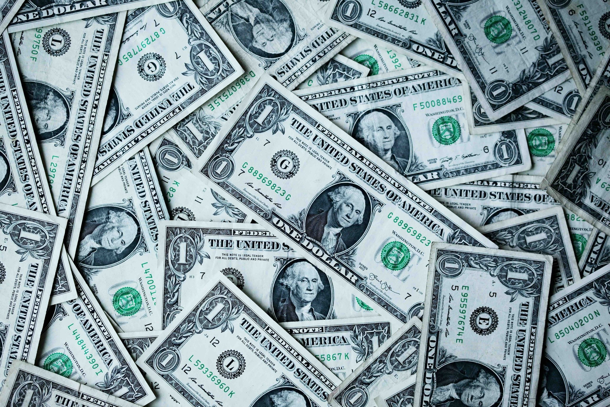 A chaotic pile of overlapping one-dollar bills.