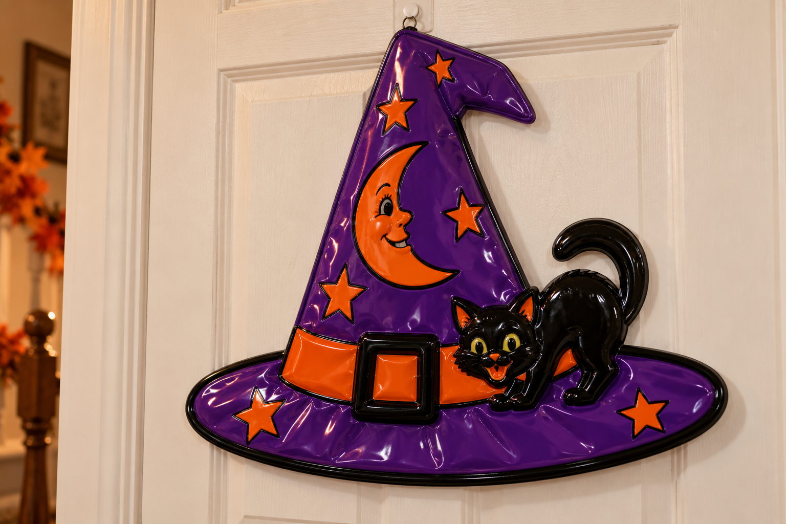 Purple witch hat wall decoration featuring an orange crescent moon with a face, an orange hat band with a black buckle, and a black cat.