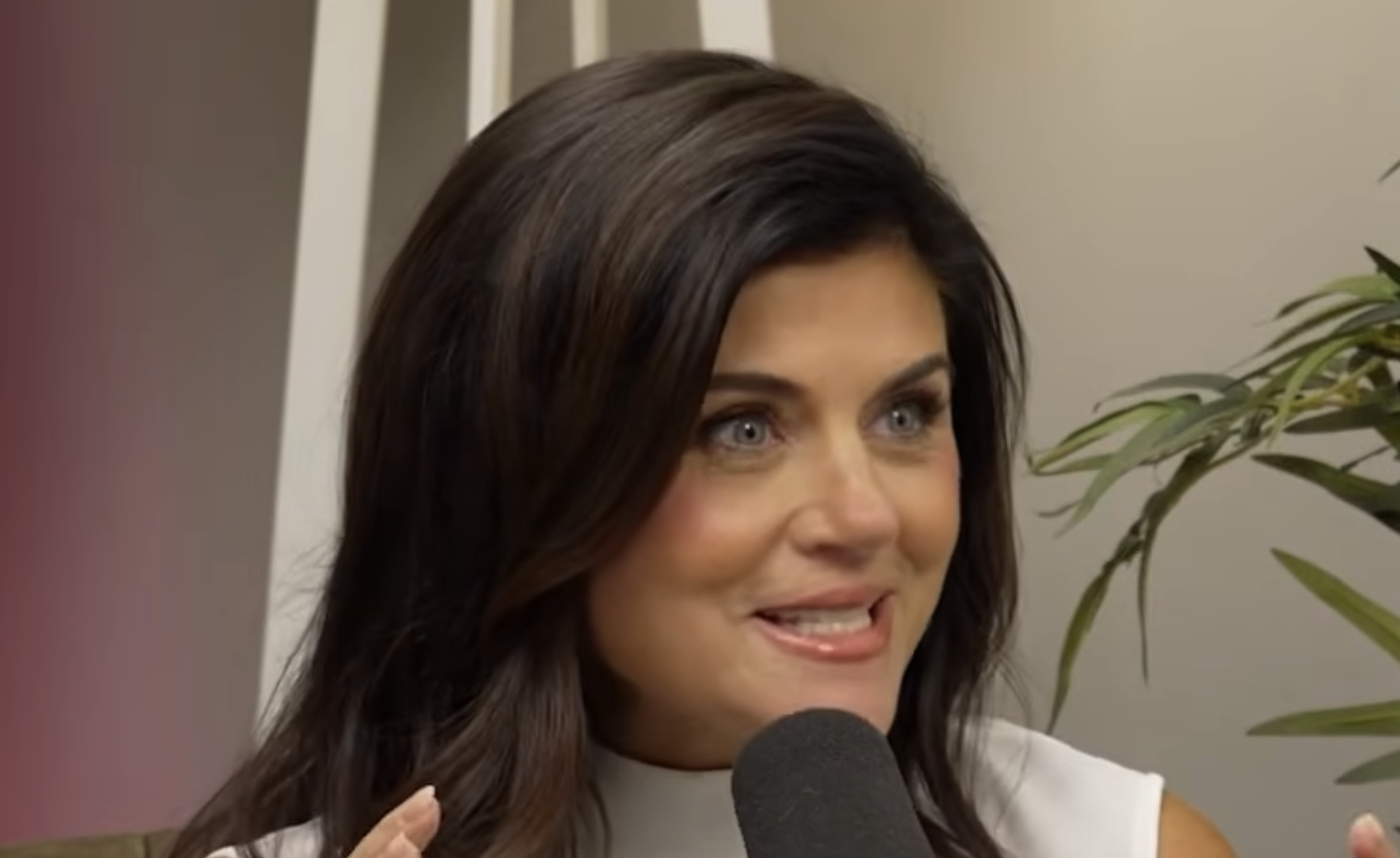 A woman with dark hair speaks into a microphone.