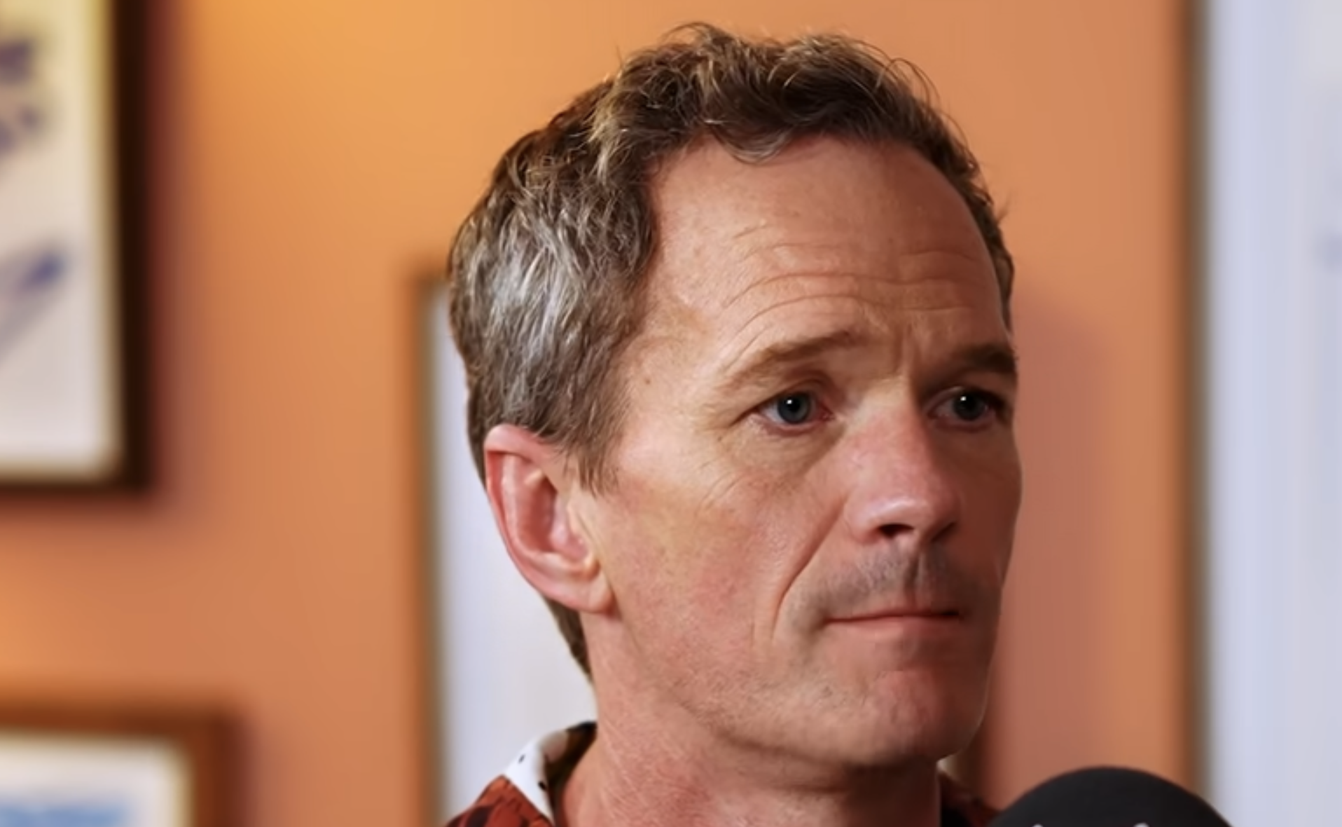 A middle-aged man with short, textured hair looking off-camera.