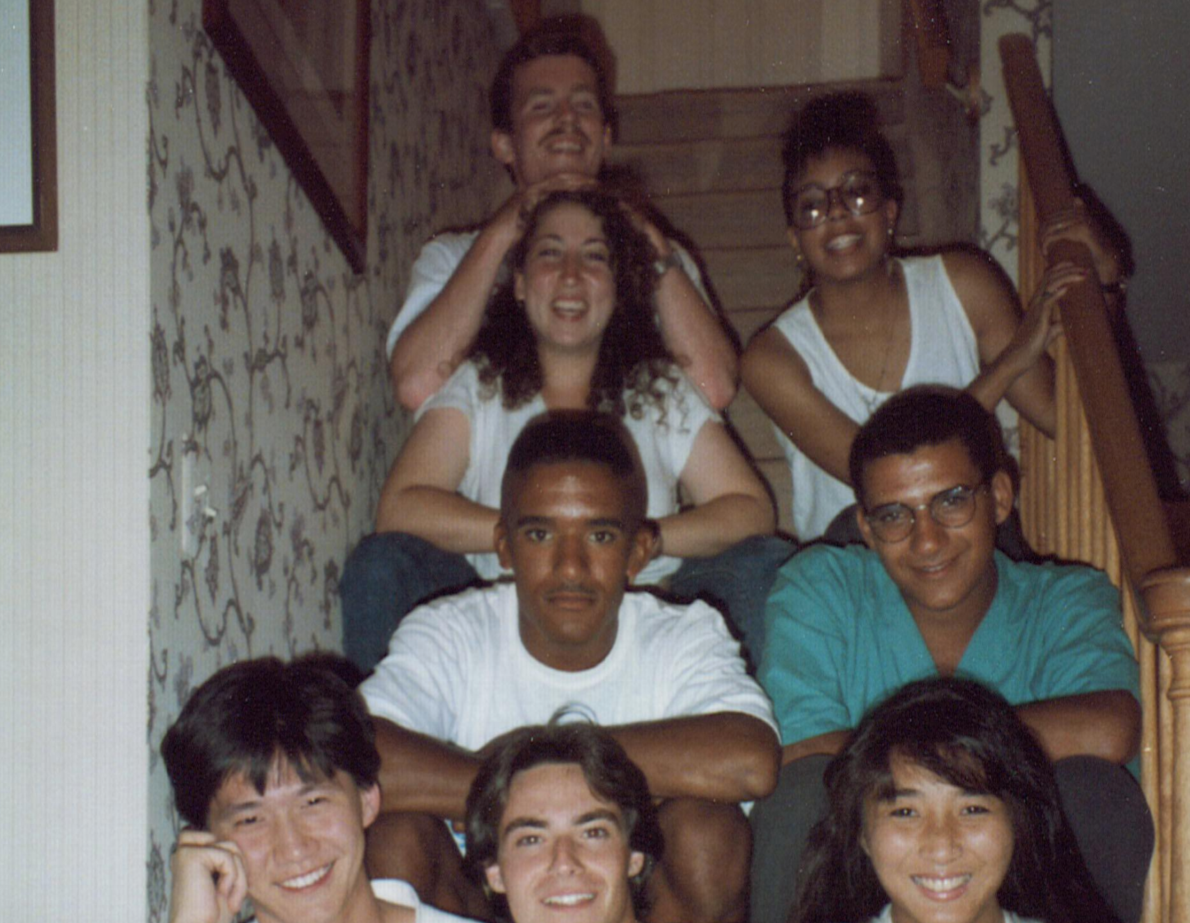 Seven young adults pose for a group photo while sitting on a staircase.