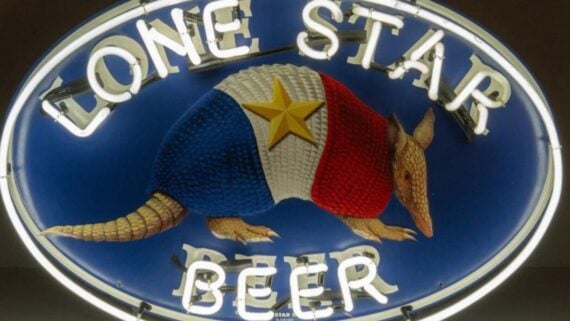 Oval neon sign for Lone Star Beer featuring an armadillo patterned with the Texas flag and a gold star.