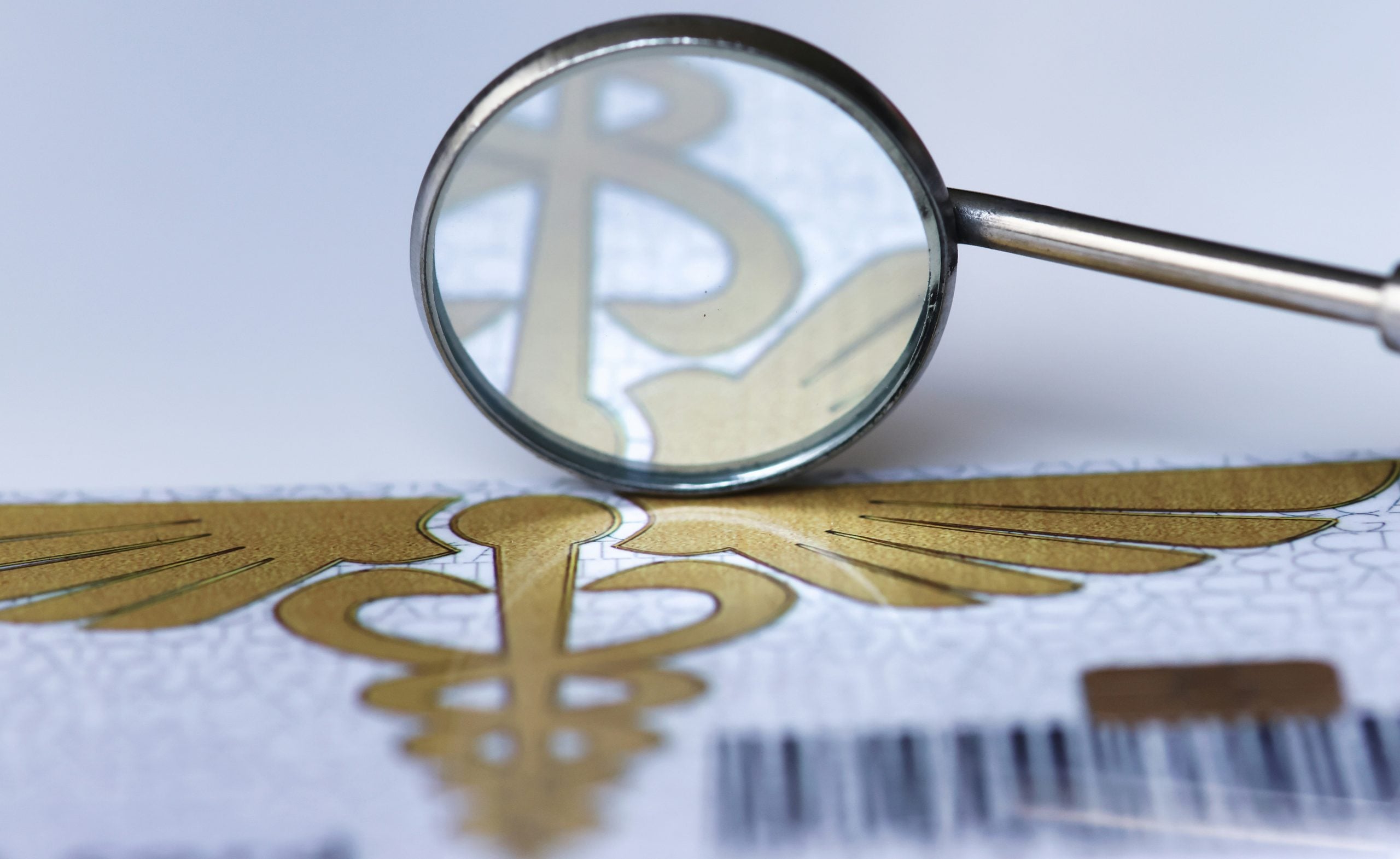 A dental mirror reflecting the gold caduceus symbol printed on a medical document.
