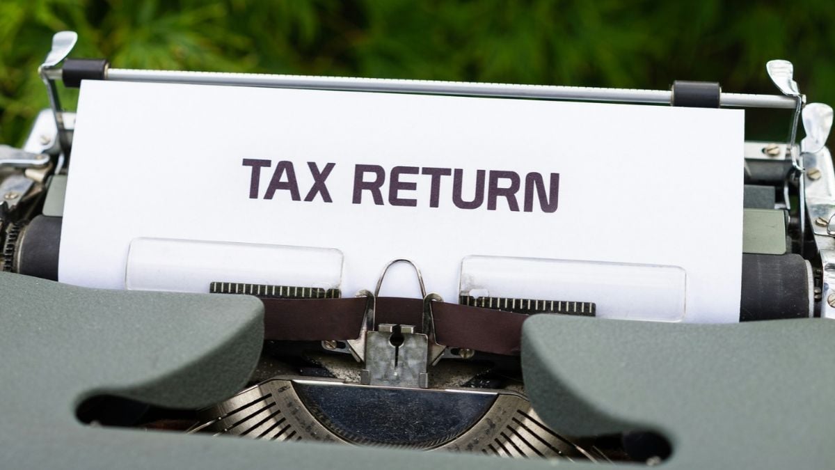A close-up of a typewriter with paper inserted that reads “TAX RETURN” in bold capital letters.