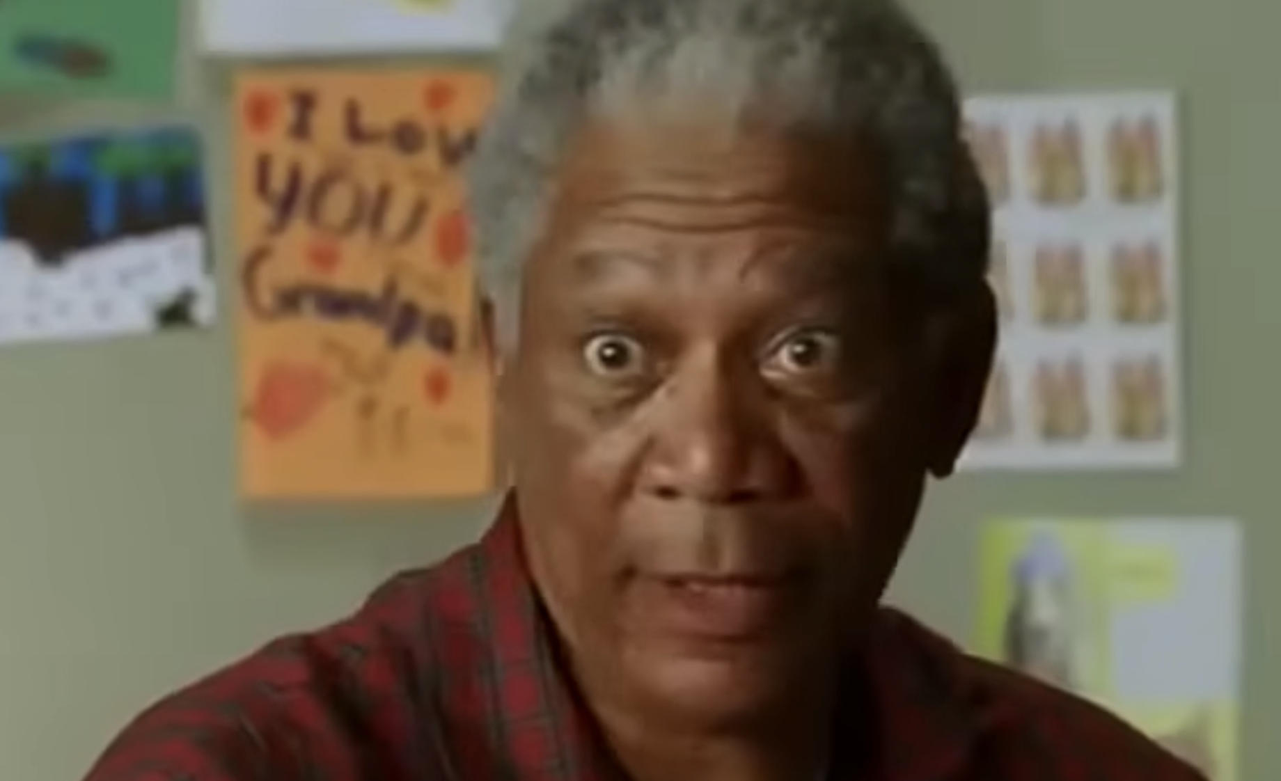 Morgan Freeman looking surprised in front of a wall with children’s drawings.