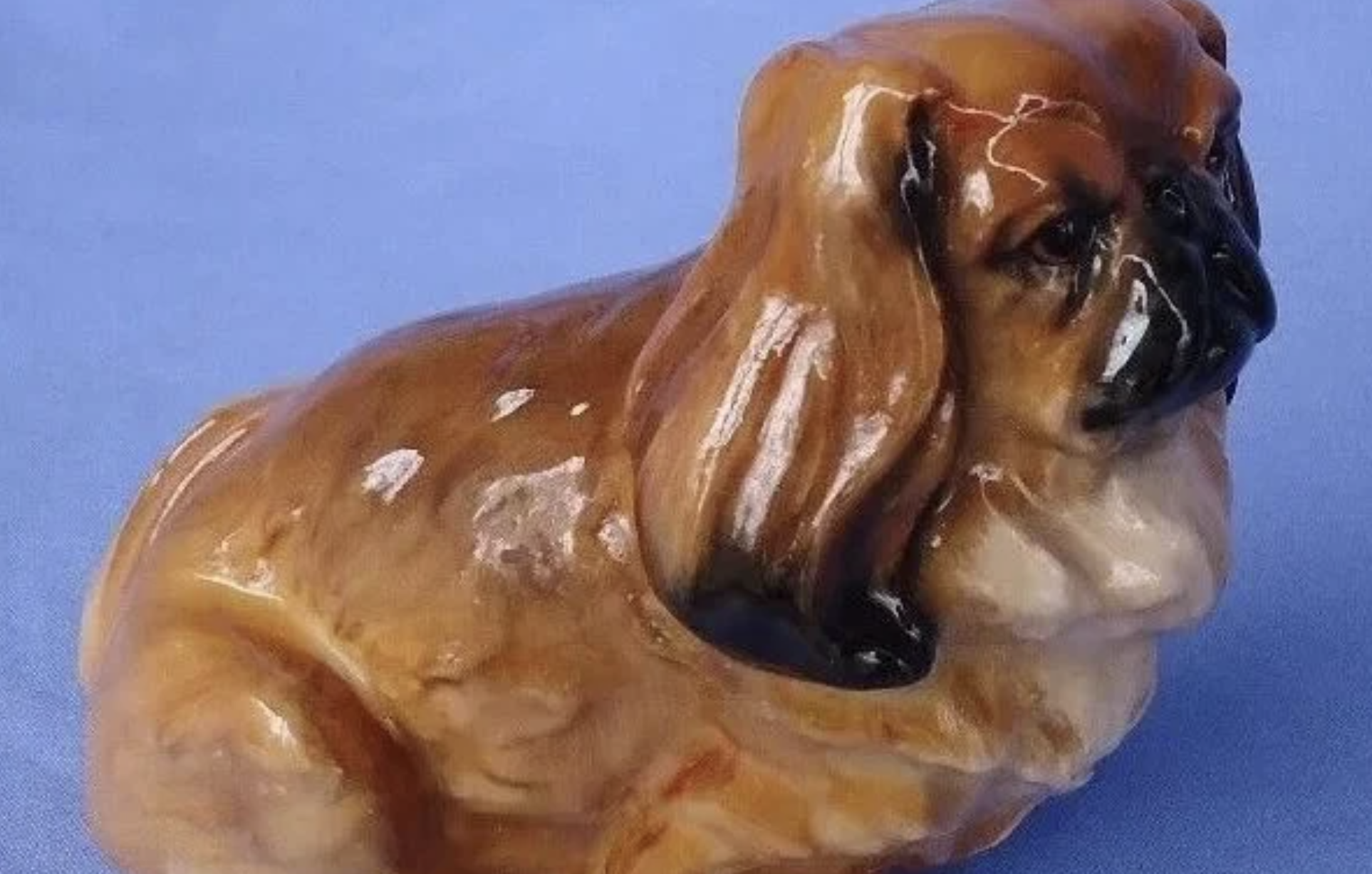 Ceramic figurine of a brown and black Pekingese dog.