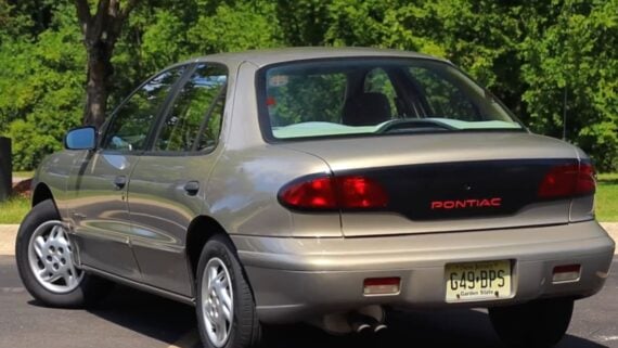 Gold Pontiac sedan viewed from the rear right, with a New Jersey license plate reading G49-BPS.