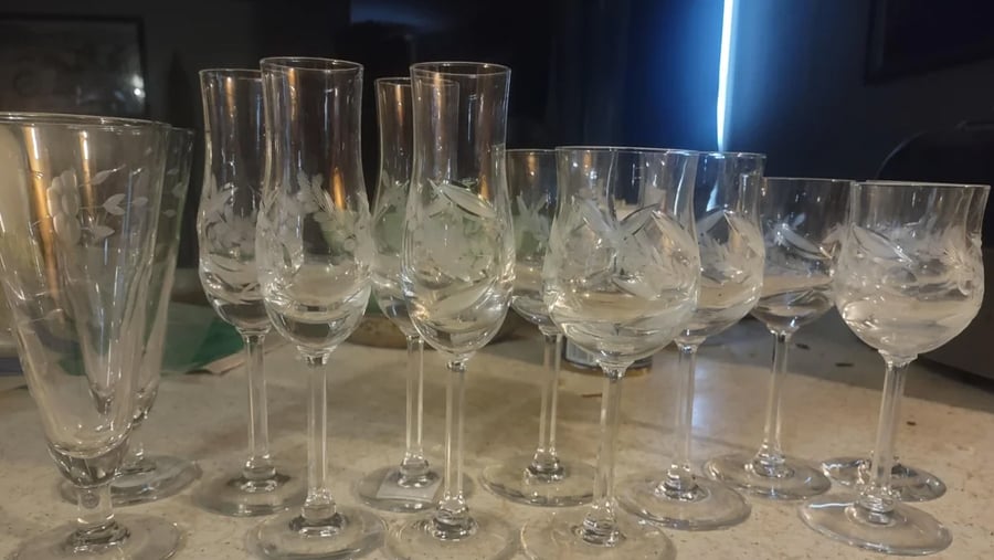 A collection of various clear glass stemware, each featuring delicate floral etchings.