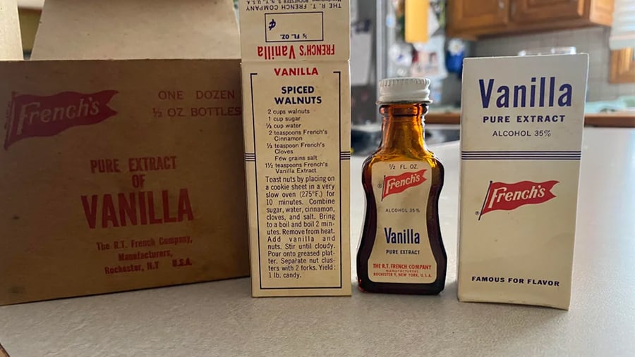 A vintage French’s Pure Extract of Vanilla set including a cardboard shipping box, a tall carton with a spiced walnut recipe, a small amber glass bottle, and a white product box.