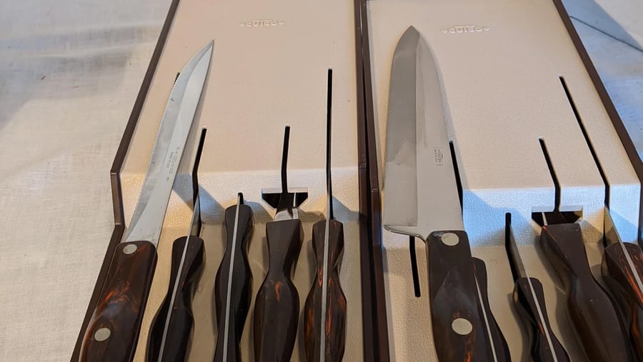 A set of Cutco knives with dark marbled handles arranged in two open, fitted presentation boxes.