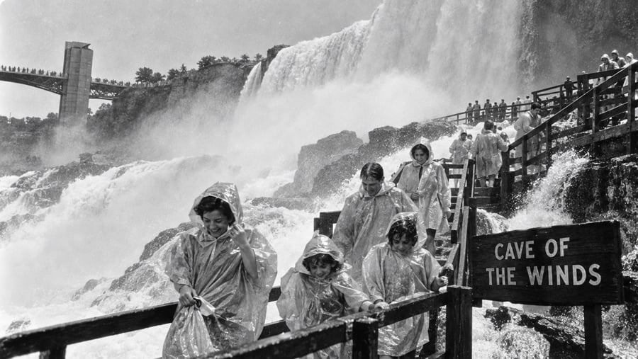 People in plastic ponchos walking on a wooden walkway near the Cave of the Winds at Niagara Falls.