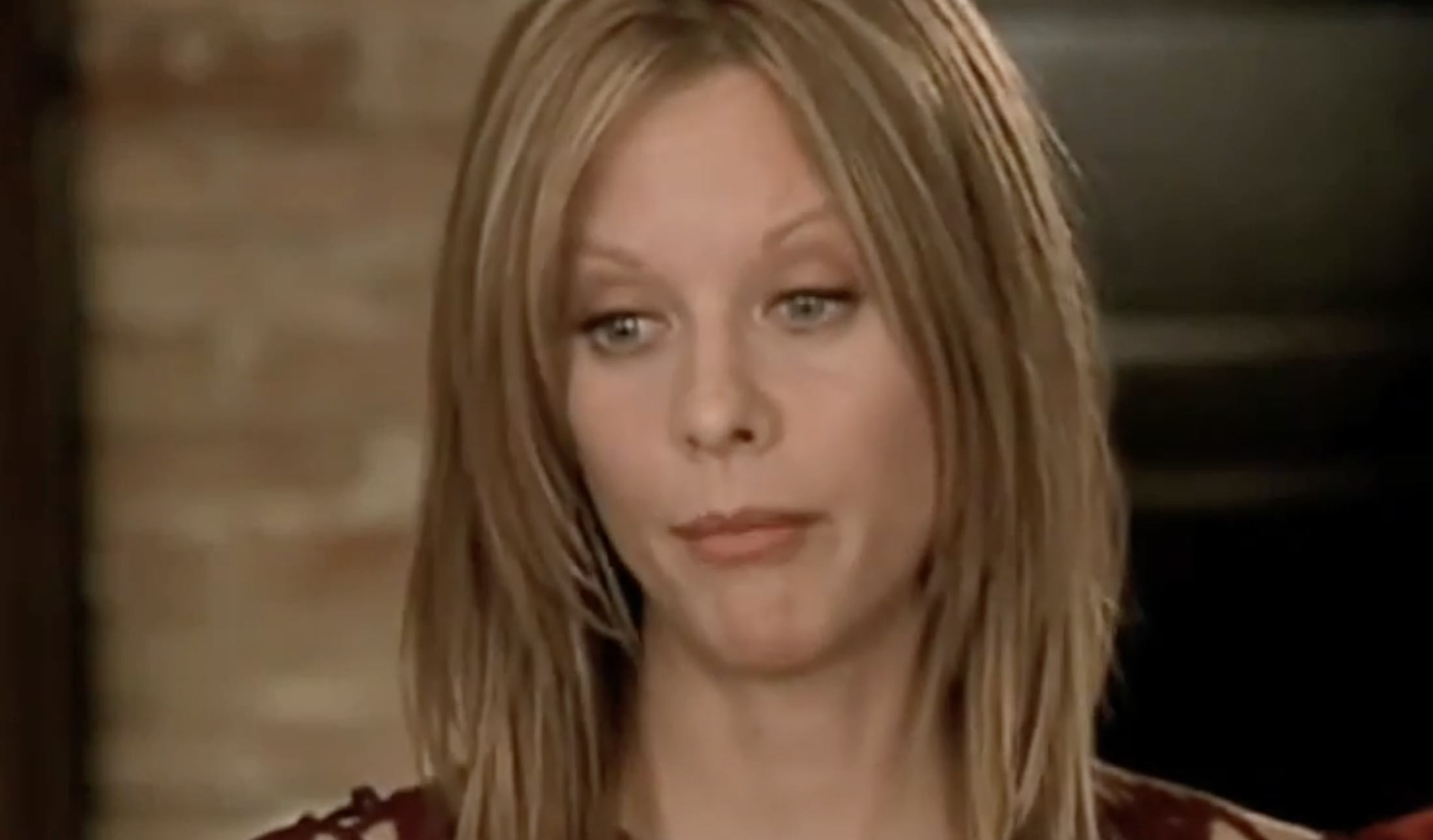 A woman with shoulder-length blonde hair looking forward with a neutral expression.
