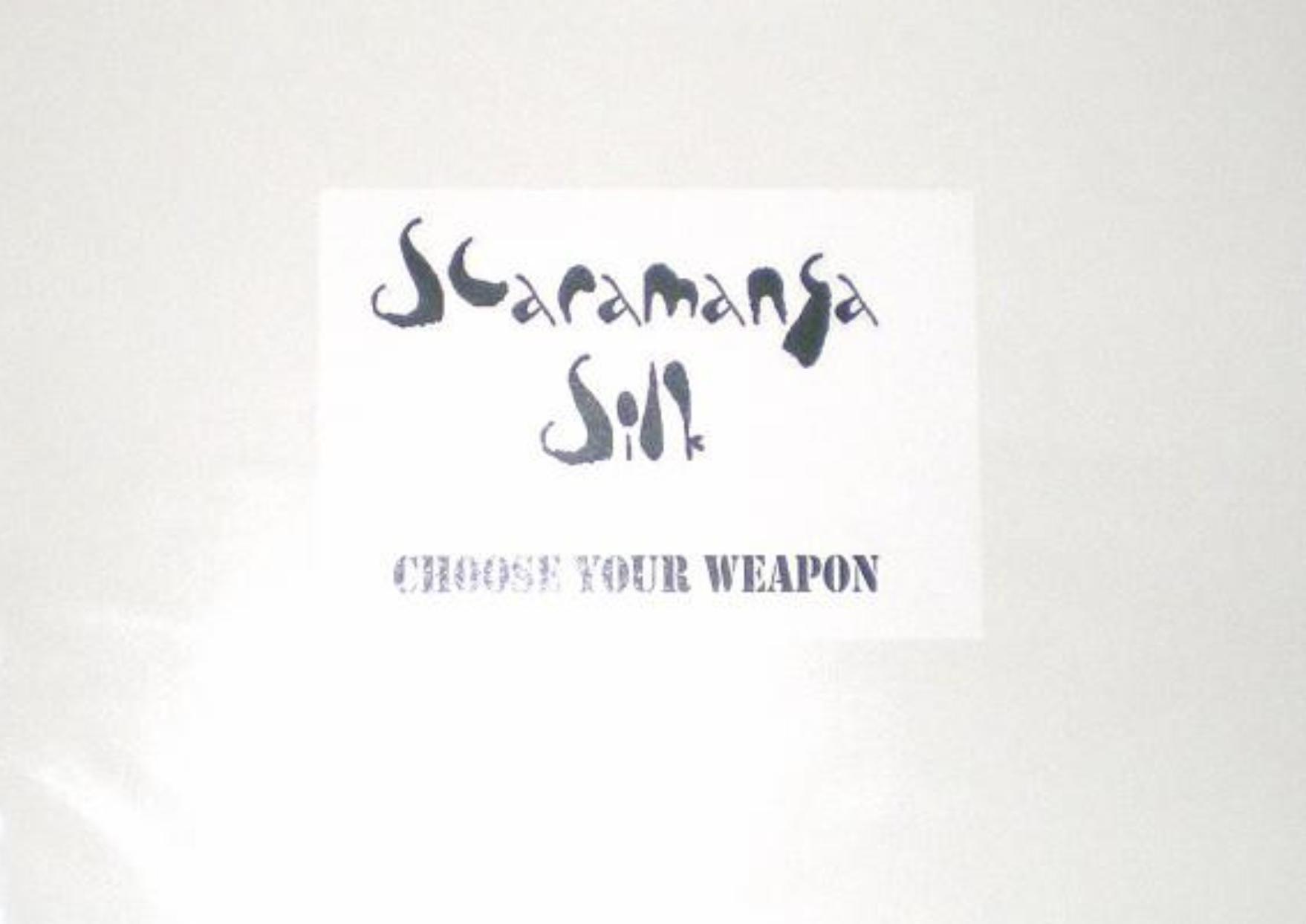 White sign with the text “Scaramanga Silk” in stylized black font above the words “CHOOSE YOUR WEAPON” in stencil-style lettering.