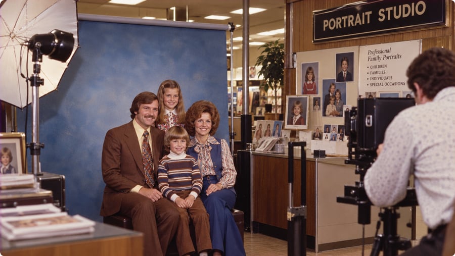 A photographer takes a portrait of a family of four in a studio.