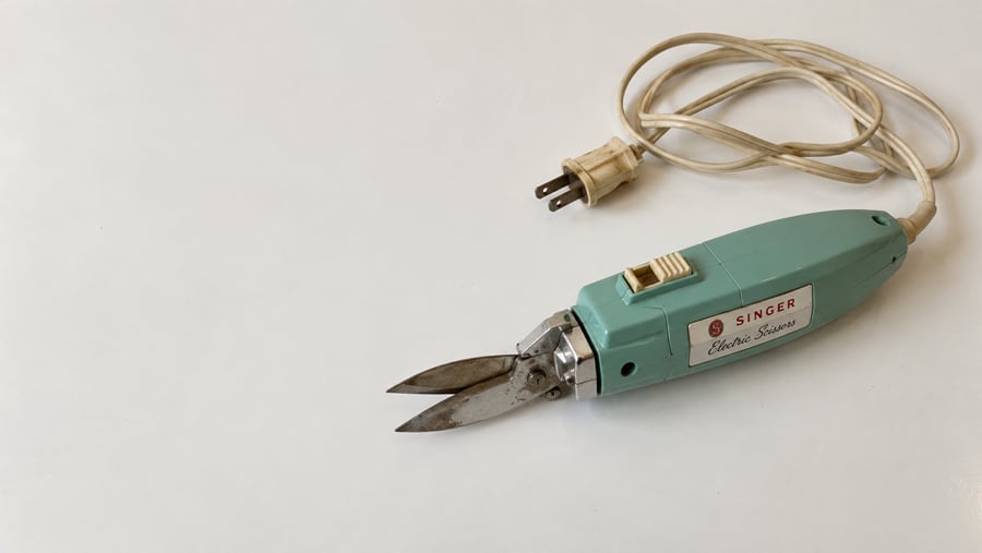 Vintage Singer electric scissors with a teal handle and attached power cord.
