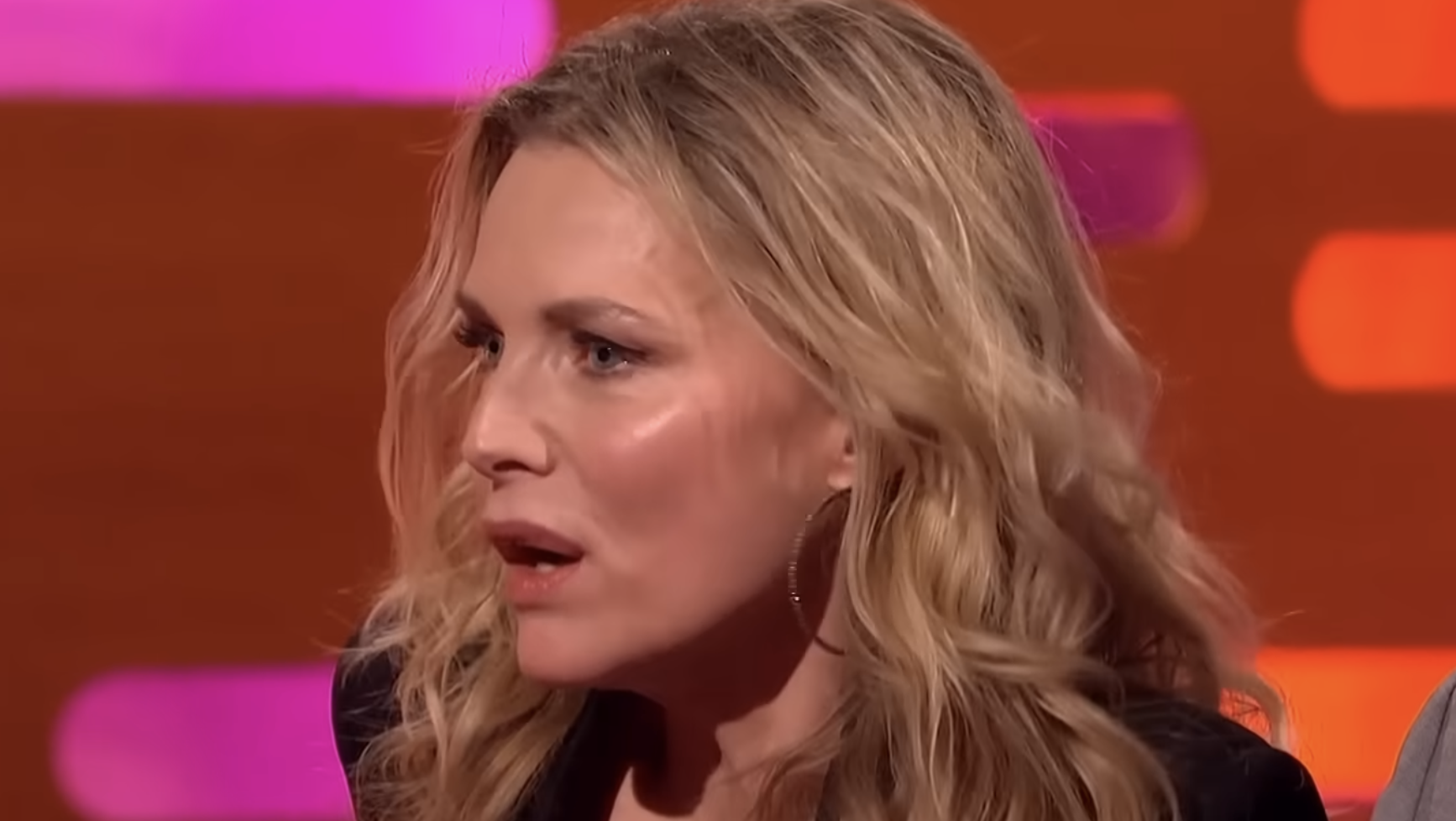 Michelle Pfeiffer speaking on a television talk show set.