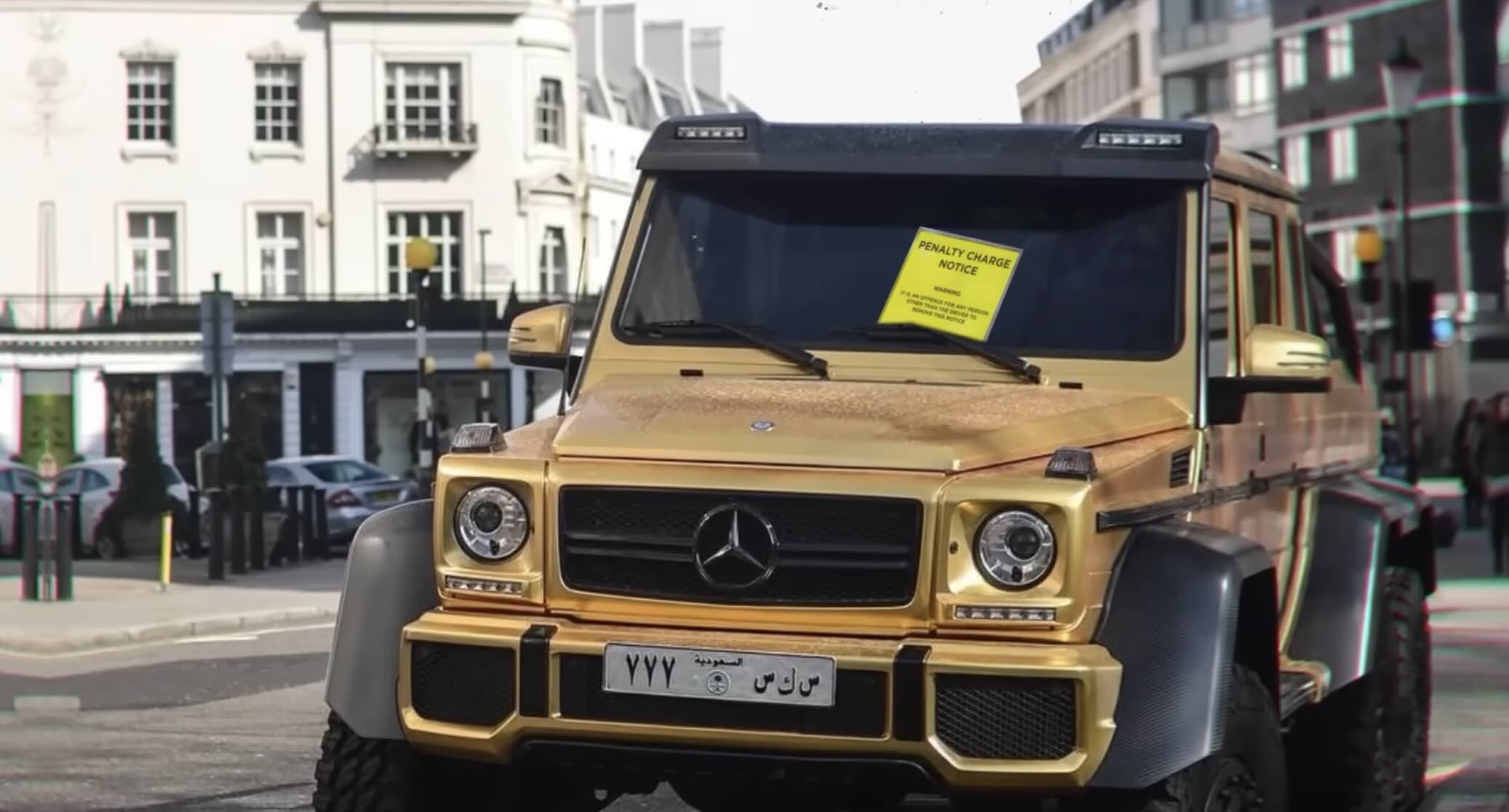 A gold Mercedes-Benz G-Wagon parked on a city street with a yellow penalty charge notice attached to the windshield.