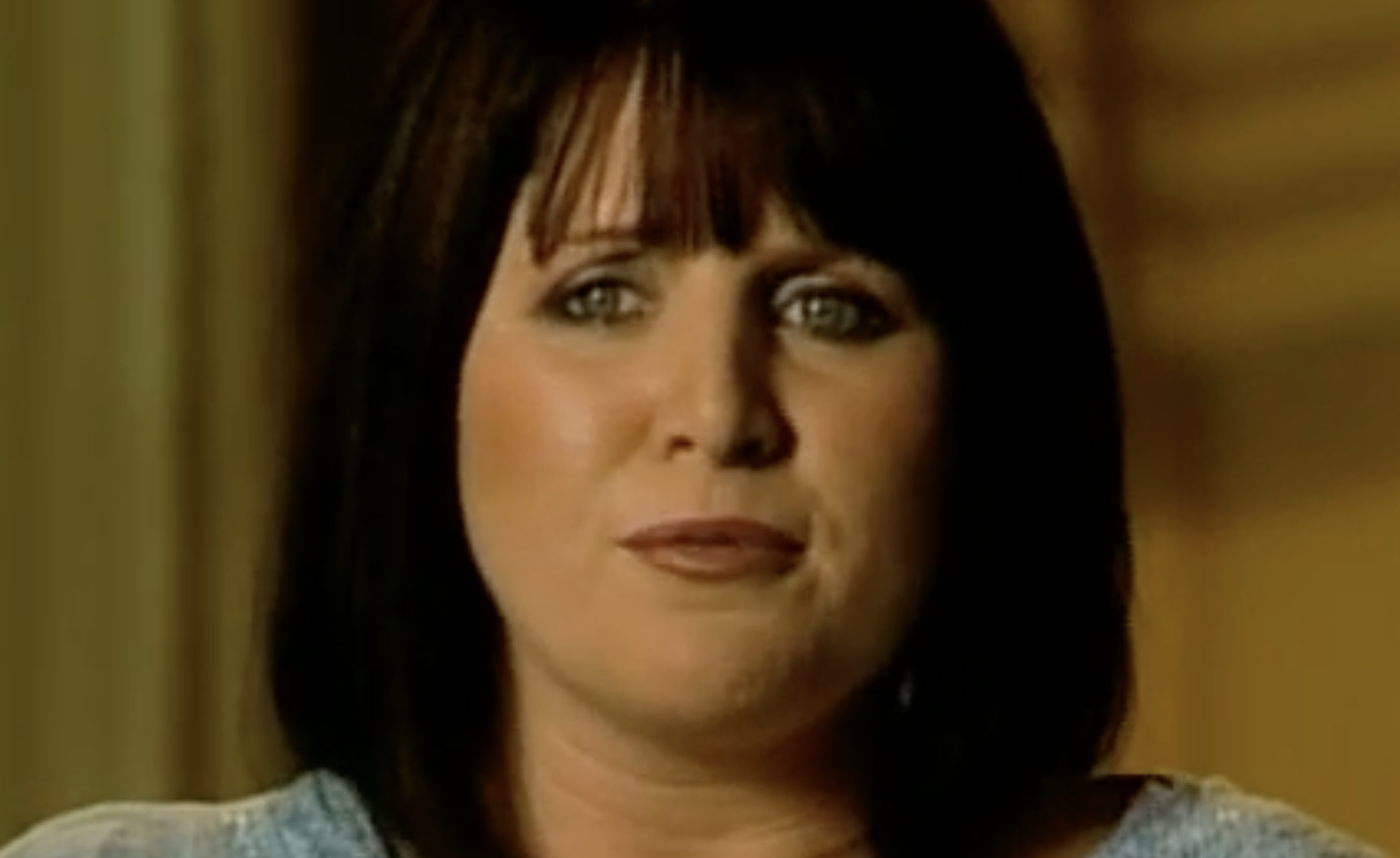 A woman with dark hair and bangs looking directly at the camera with a neutral expression.