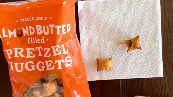 A bag of Trader Joe’s almond butter filled pretzel nuggets next to two nuggets on a paper towel, one of which is split open.