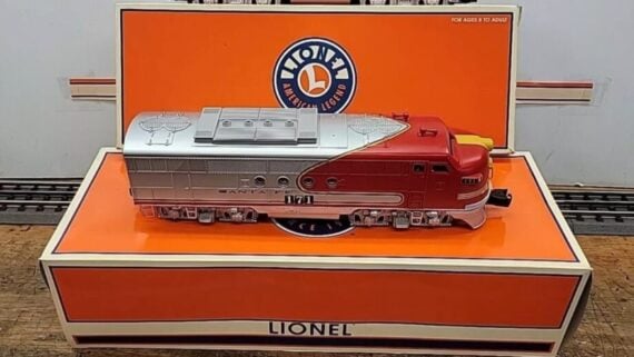 A red and silver Lionel Santa Fe model train locomotive displayed in front of its original branded box.