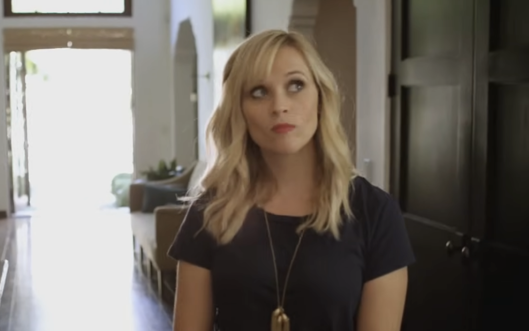 Reese Witherspoon looking upward with a thoughtful expression.