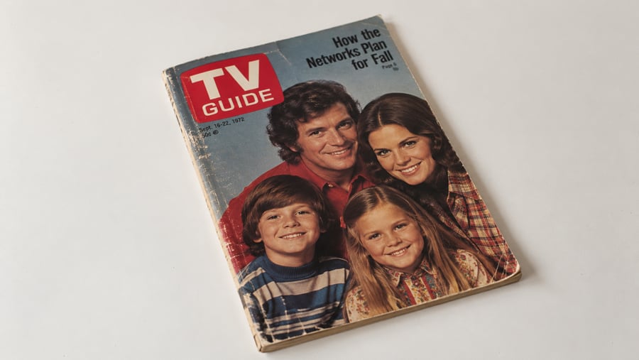 A vintage TV Guide magazine from 1977 features a smiling family of four on the cover, with the headline “How the Networks Plan for Fall!” The magazine has worn edges and sits on a plain white background.